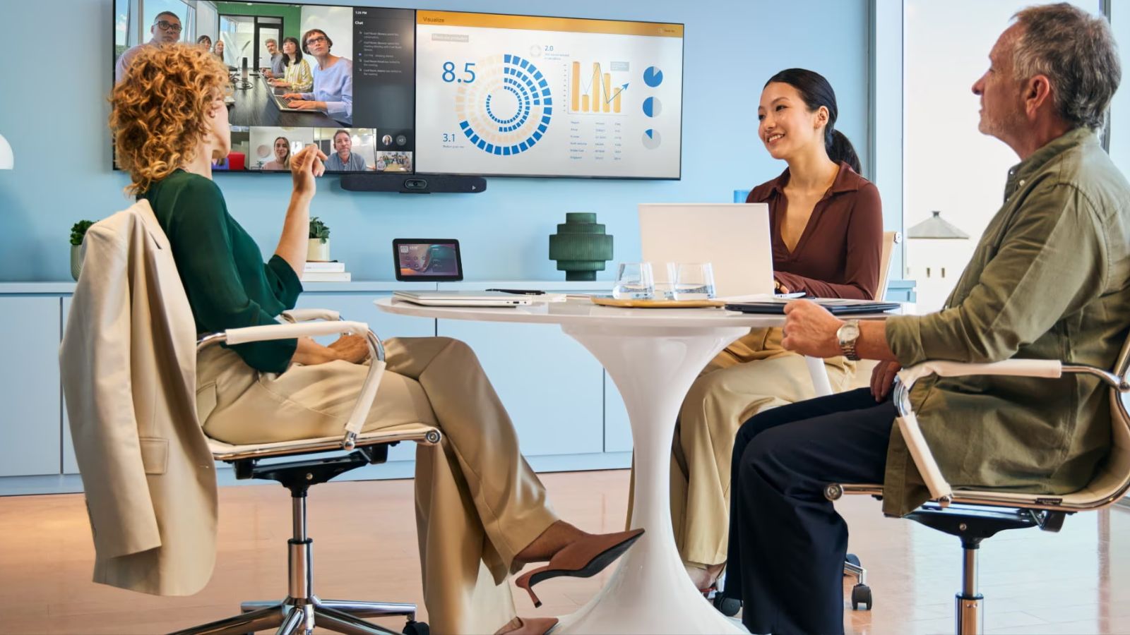 Hybride vergaderruimte met professionals in meeting, videobar toont remote deelnemers op dual-screen setup